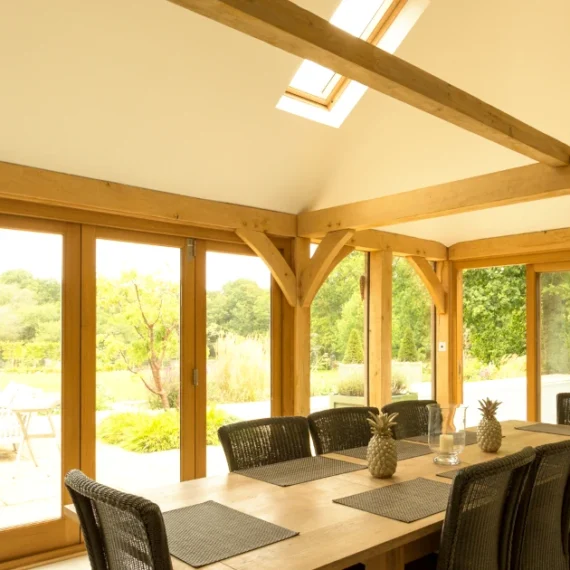 Oak framed home extension showing aesthetic value through exposed beams, natural light, and luxury dining space, demonstrating oak's impact on property value