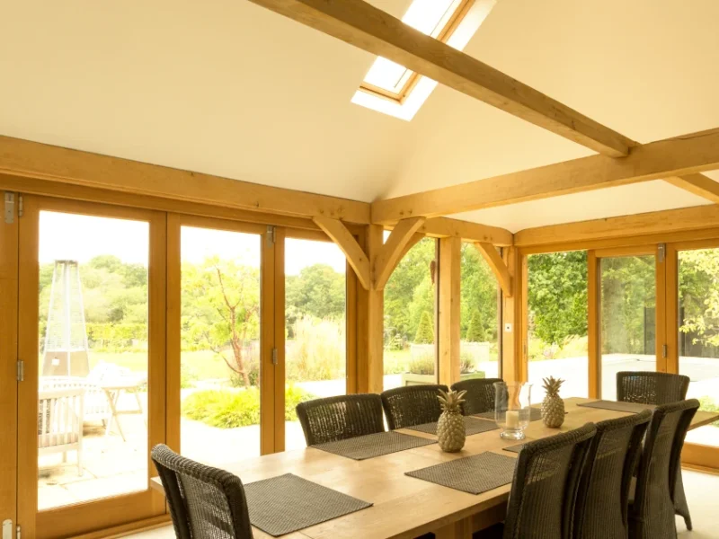 Oak framed home extension showing aesthetic value through exposed beams, natural light, and luxury dining space, demonstrating oak's impact on property value