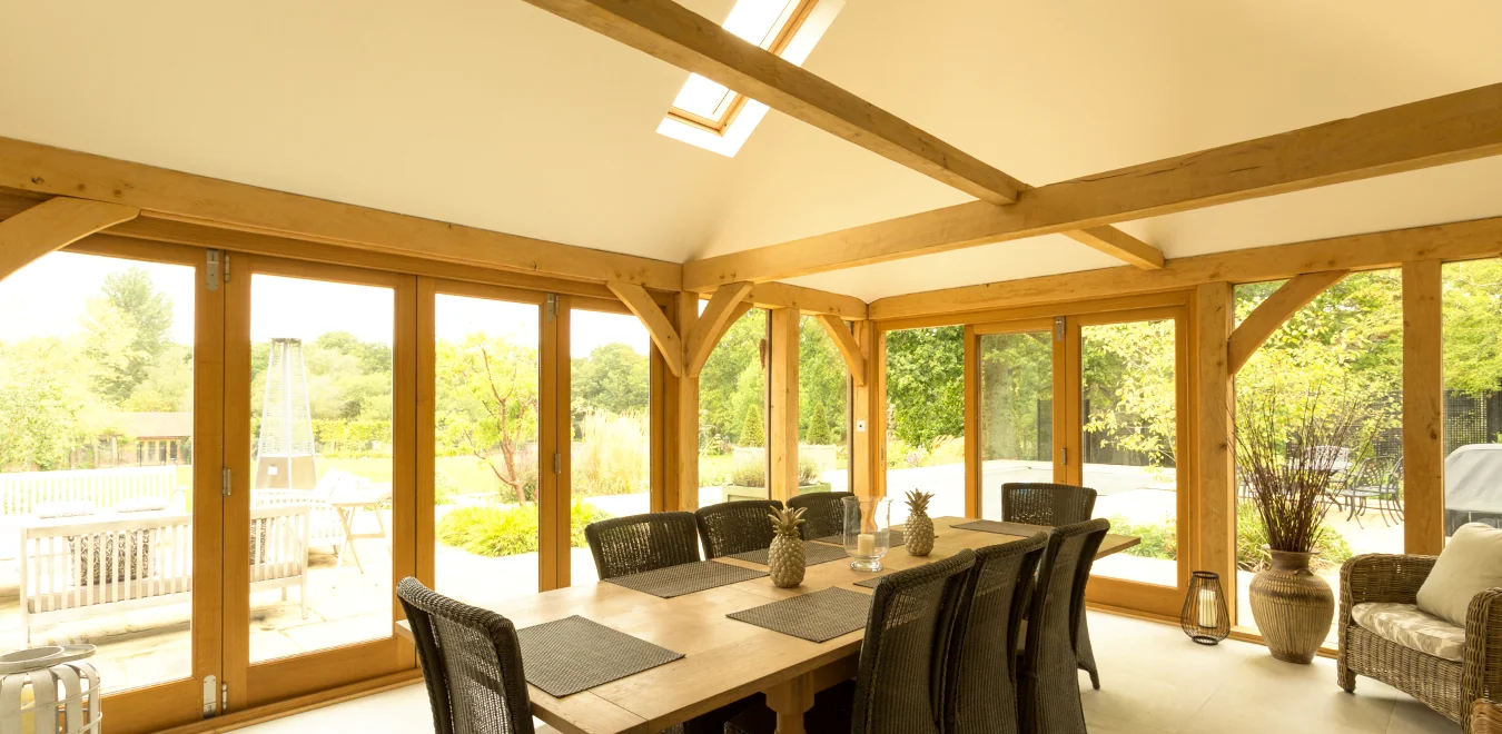 Luxury oak framed garden room featuring exposed oak beams, floor-to-ceiling glazing, and a contemporary dining space flooded with natural light