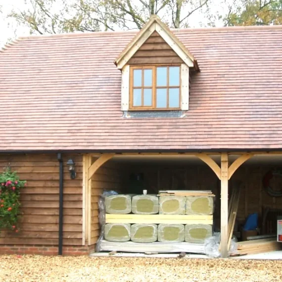 Insulating your oak framed building: a wooden oak framed building with insulation materials stacked in the open garage area