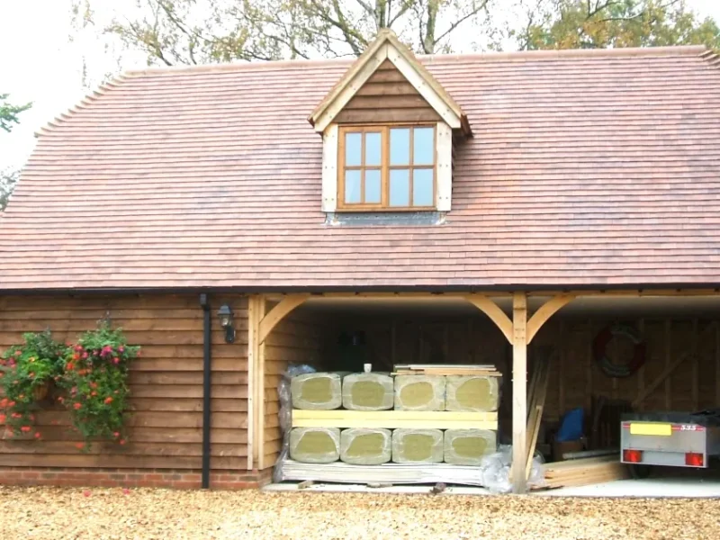 Insulating Your Oak Framed Building: A wooden oak framed building with insulation materials stacked in the open garage area