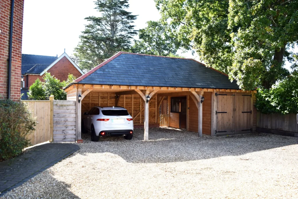 A spacious oak framed 3 bay garage with an attached carport by oakcraft. A white car is parked under the carport.