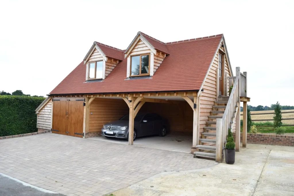 Oakcraft oak framed three bay garage with loft space. Features include exposed beams, dormer windows, and an external staircase.