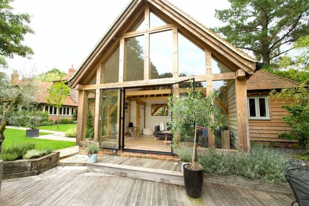 Contemporary oak framed annexe with full-height glazing, opening onto a decked patio and landscaped garden.