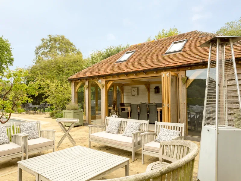 Bespoke oak-framed garden annexe by oakcraft, ideal for luxury guest accommodation with a cosy outdoor area.