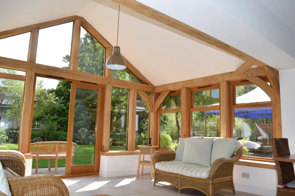 Bespoke oak framed building in Dorset featuring handcrafted oak frame, vaulted ceiling with exposed beams, floor-to-ceiling windows, and luxury garden room furnishings