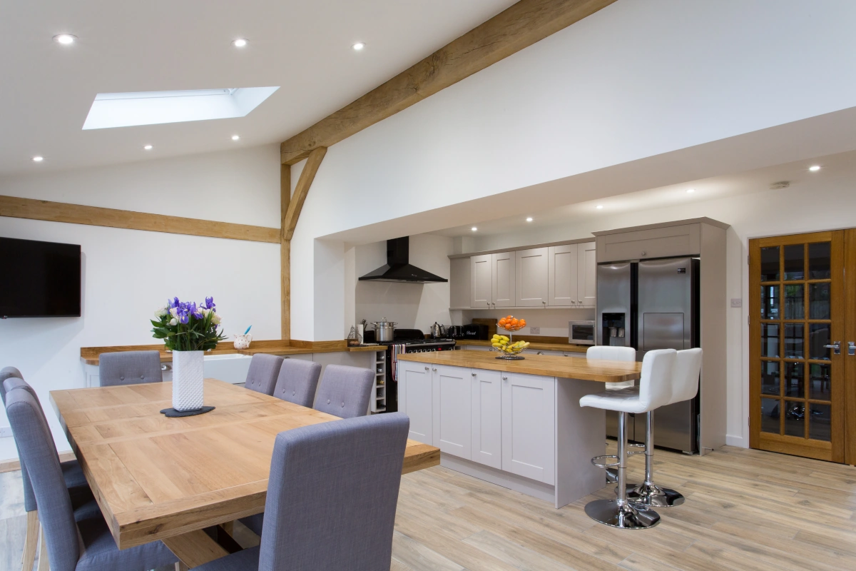 Oak-framed kitchen-diner featuring vaulted ceiling, grey shaker units, wooden worktops, dining table and oak beam details