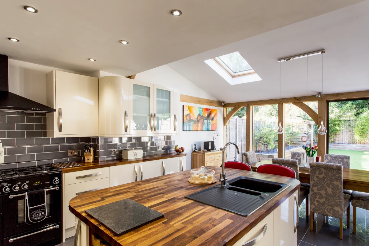 Pen-plan kitchen featuring cream units, wooden worktops, range cooker and oak-framed garden views