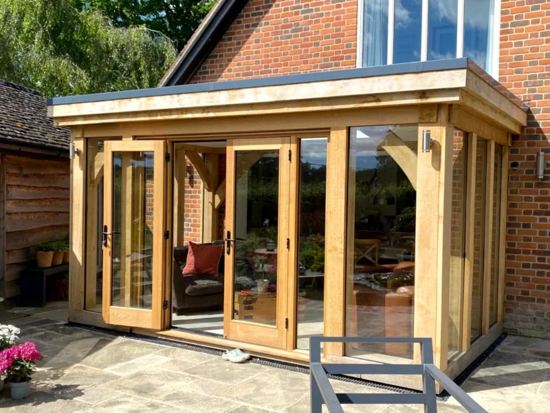 Modern oak-framed orangery featuring full-width bi-fold doors, York stone paving and brick detailing, showcasing contemporary orangery design in Hampshire