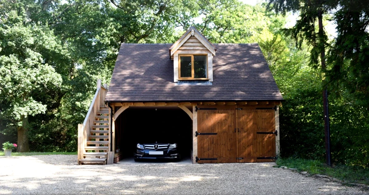 A beautifully crafted oak framed garage. Our oak outbuildings can be designed to include both garage and carport functionality. Providing secure parking and additional storage space for any UK home. This oak outbuilding features a loft space accessed by external stairs.