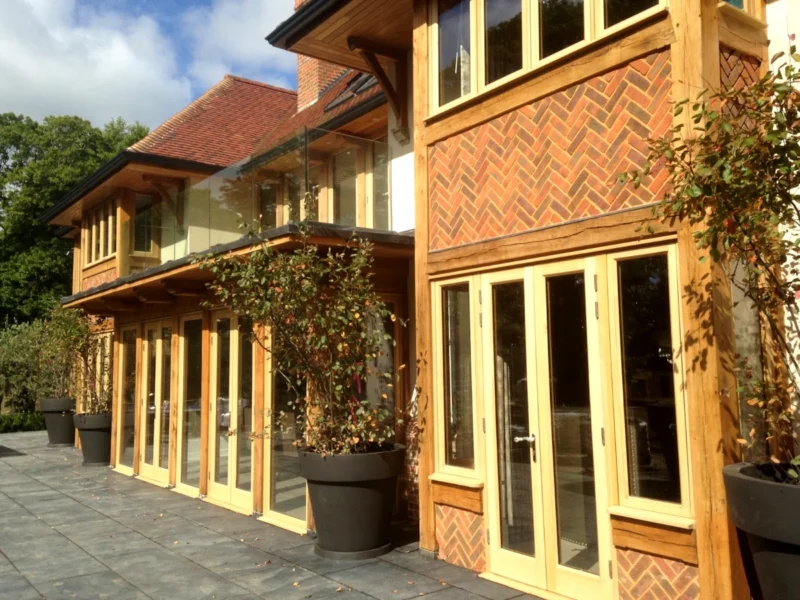 Modern oak framing used in this oak framed building with floor-to-ceiling glazing, decorative brickwork and clay tiled roof, built in Hampshire