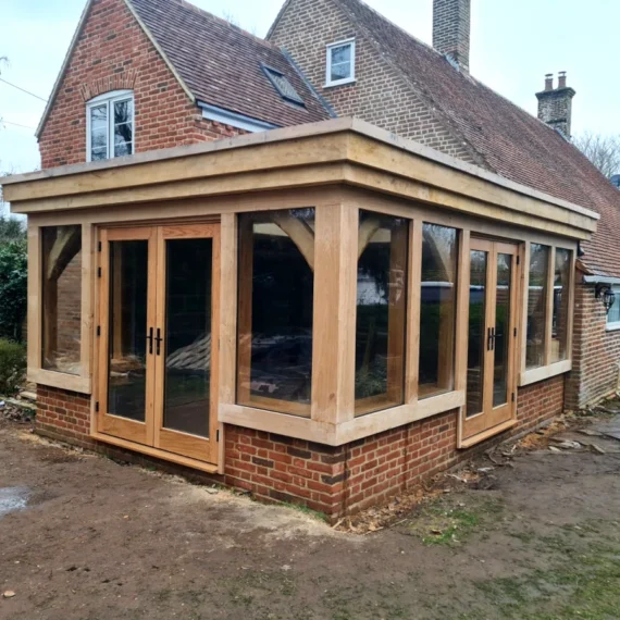 Recently completed oak framed orangery featuring engineered oak french doors, direct glazing, and traditional brick base in blashford, hampshire