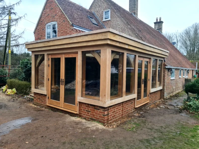 Recently completed oak framed orangery featuring engineered oak French doors, direct glazing, and traditional brick base in the New Forest, Hampshire