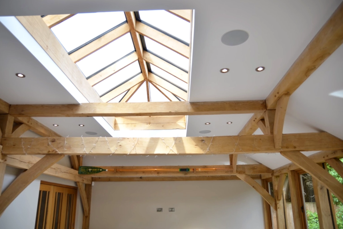 Interior view of oak-framed orangery showing exposed beams, roof lantern and recessed lighting, showcasing traditional hampshire joinery