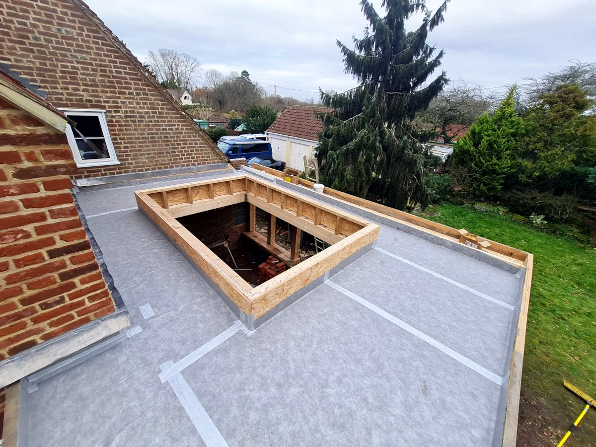 Warm flat roof system with oak lantern opening during orangery construction in hampshire, showing grp membrane and timber upstand