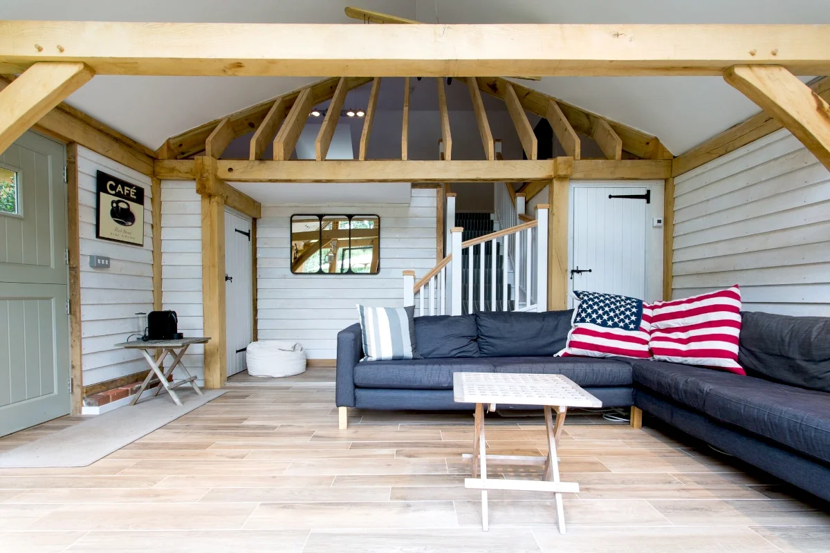 Oak Framed Extensions Hampshire Interior of oak framed extension in Hampshire featuring exposed beams, vaulted ceiling, timber cladding, wooden flooring and comfortable seating area