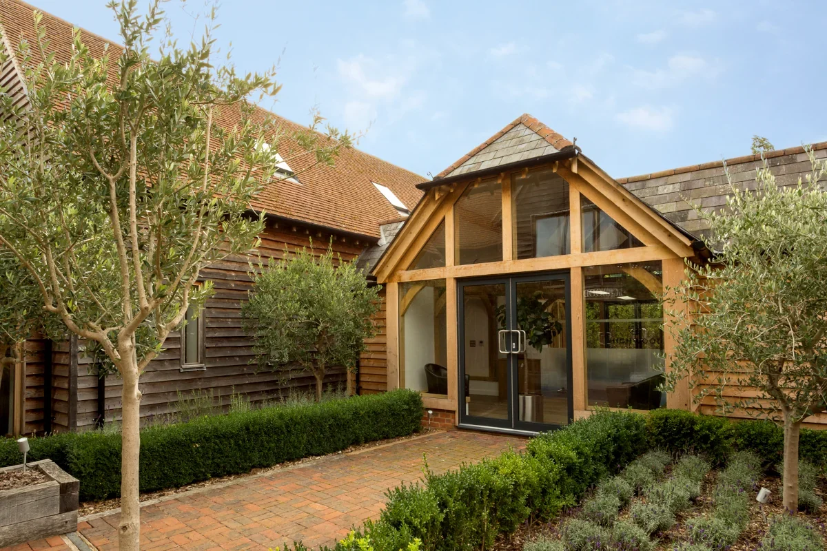 Oak Framed Extensions Hampshire Classic oak framed extension in Hampshire featuring gabled roof, full-height glazing and sliding doors surrounded by Mediterranean-style garden with olive trees and lavender