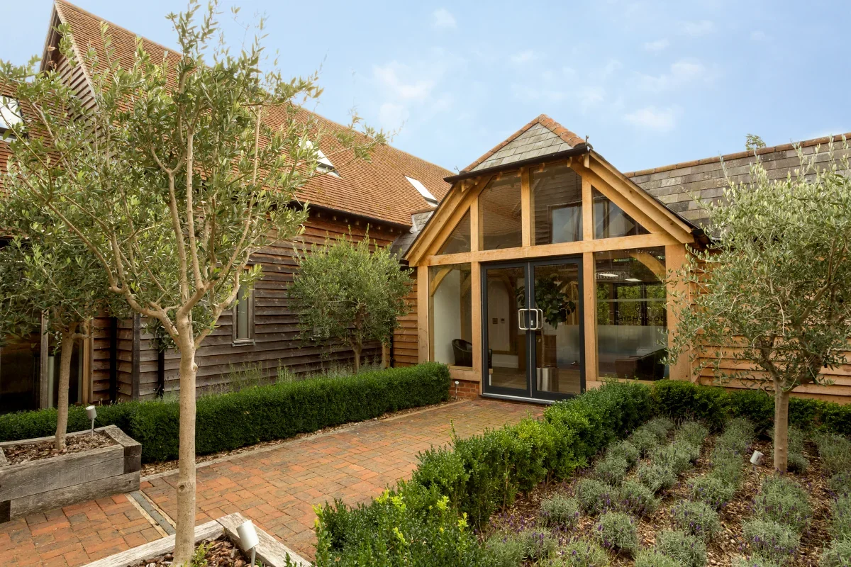 Oak Framed Buildings Hampshire Front view of a stunning oak-framed building in Hampshire with landscaped gardens and a rustic design.