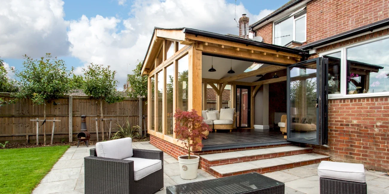 Oak Framed Extensions Hampshire Oak framed extension Hampshire with vaulted ceiling, bifold doors opening onto stone patio area and landscaped garden